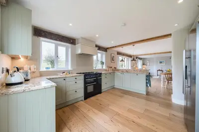 a large kitchen with white cabinets and wooden floors at Glebe Cottage, Little Petherick, near Padstow in Little Petherick