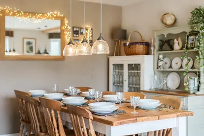a dining room with a table with plates and glasses at Glebe Cottage, Little Petherick, near Padstow in Little Petherick