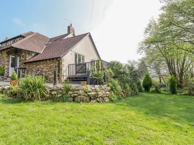 a house with a stone wall in the yard at Little Oaklands in Lostwithiel