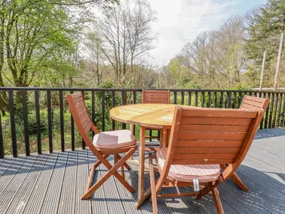 a wooden table and two chairs on a deck at Little Oaklands in Lostwithiel