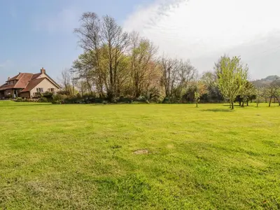 a field of green grass with a house in the background at Little Oaklands in Lostwithiel