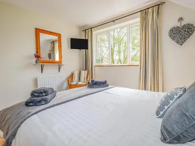 a bedroom with a large white bed and a window at Little Oaklands in Lostwithiel