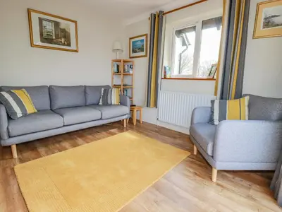 a living room with two blue couches and a rug at Little Oaklands in Lostwithiel