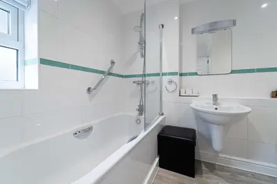 a white bathroom with a sink and a shower at The Barn in St Ives