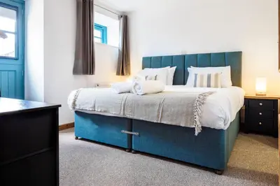 a bedroom with a large bed with a blue headboard at Kerensa in Mawnan