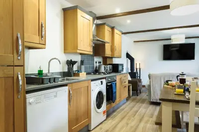 a kitchen with wooden cabinets and a washer and dryer at Kerensa in Mawnan