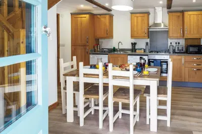 a kitchen with a table and chairs in a room at Kerensa in Mawnan