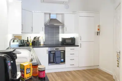 a kitchen with white cabinets and a sink at Coverack in Budock Water