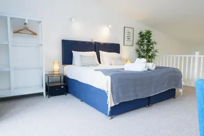 a bedroom with a large blue bed with white pillows at Helford in Mawnan