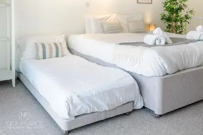 two beds with white sheets and a stuffed animal on them at Helford in Mawnan