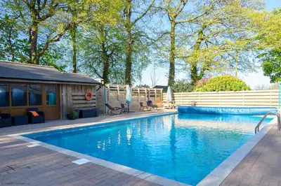 a swimming pool in a yard next to a house at Helford in Mawnan