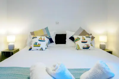 a bedroom with a bed with white sheets and pillows at Lamorna in Mawnan Smith