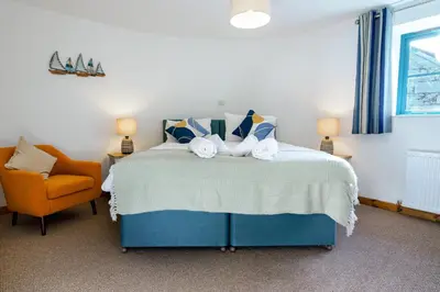 a bedroom with a blue bed and a orange chair at Lamorna in Mawnan Smith