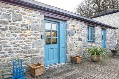 a stone house with a blue door and a patio at Manacles in Mawnan