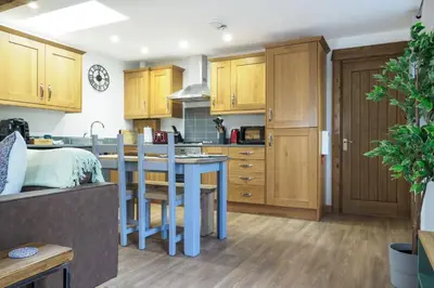 a kitchen with wooden cabinets and a blue table at Manacles in Mawnan