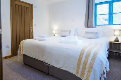 a bedroom with a large bed with white sheets and pillows at Manacles in Mawnan