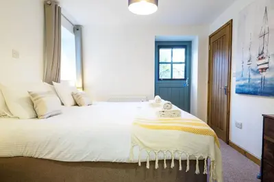 a bedroom with a large bed with white sheets and pillows at Manacles in Mawnan