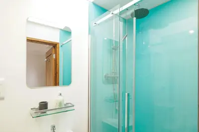 a bathroom with a glass shower with a mirror at Manacles in Mawnan