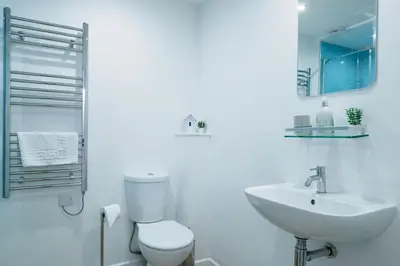 a white bathroom with a toilet and a sink at Mousehole in Mawnan