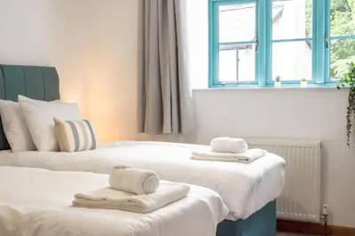 two beds with towels on them in a bedroom at Newlyn in Budock Water