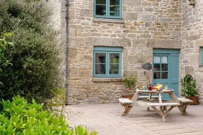 a picnic table in front of a stone building at Newlyn in Budock Water