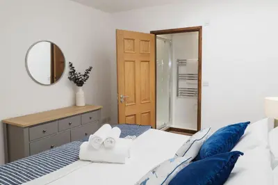 a bedroom with a bed with blue pillows and a mirror at Pendeen in Falmouth