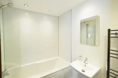 a white bathroom with a sink and a shower at Pendeen in Falmouth