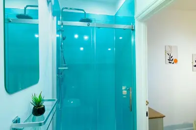 a bathroom with a shower with blue glass at Porthallow in Budock Water
