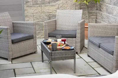 a patio with wicker chairs and a table with food on it at Porthallow in Budock Water