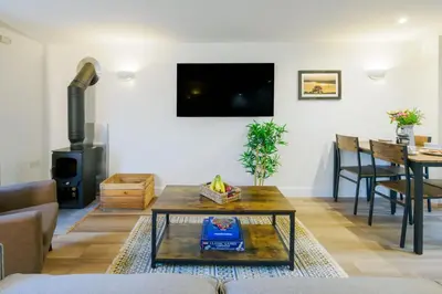 a living room with a table and a tv at Porthallow in Budock Water