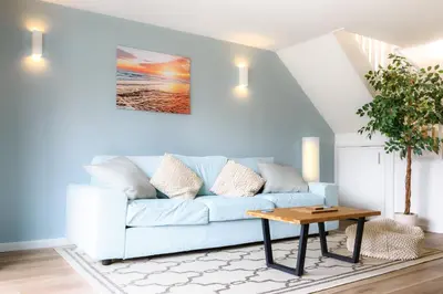 a living room with a blue couch and a table at Sennen in Budock Water