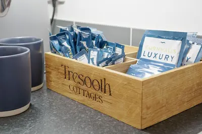 a wooden crate filled with blue packets on a counter with two cups at Sennen in Budock Water