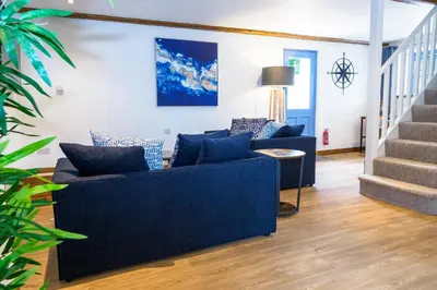 a living room with a blue couch and stairs at St Keverne in Budock Water