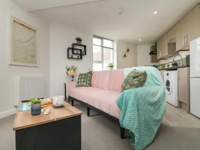 a living room with a pink couch and a table at Lighthouse Lofts - St Anthony in Camborne