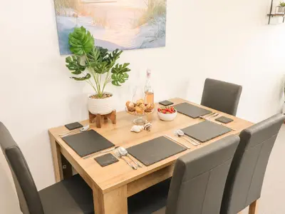 a dining room table with chairs and a wooden table with a plant at Lighthouse Lofts - St Anthony in Camborne