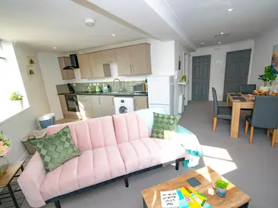 a living room with a pink couch and a kitchen at Lighthouse Lofts - St Anthony in Camborne