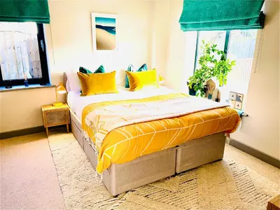 a bed with yellow pillows in a room with windows at Avalennek in Newquay