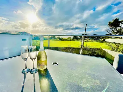a table with two glasses and a bottle of wine at Avalennek in Newquay