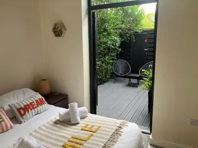 a bedroom with a bed and a patio with a deck at The Salt Box- Lovely refurbished annexe, free parking, walk to Porth beach. in Saint Columb Minor