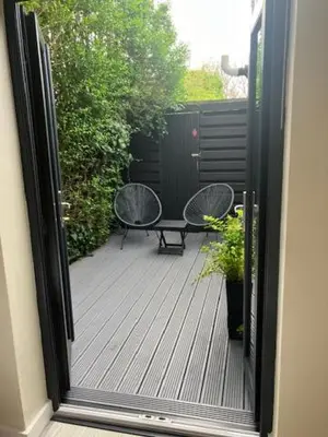 an open door to a patio with two chairs and a bench at The Salt Box- Lovely refurbished annexe, free parking, walk to Porth beach. in Saint Columb Minor