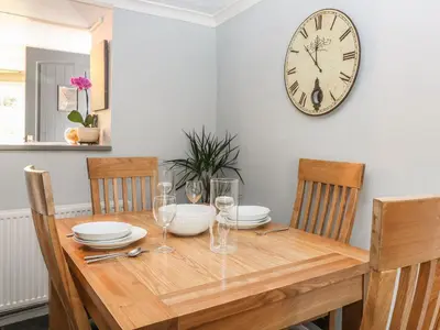 a dining room table with a clock on the wall at The Retreat in Liskeard