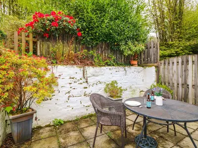 a table and chairs in a garden with a fence at The Retreat in Liskeard