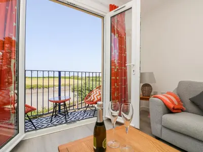 a living room with a window with wine glasses on a table at Azure in St Ives