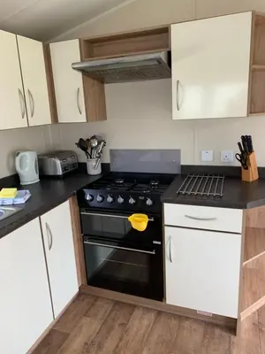 a kitchen with a black stove and white cabinets at Newquay Bay Resort 63 in Porth