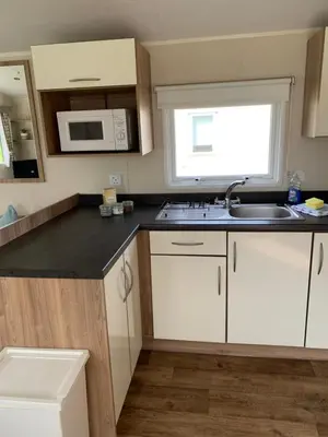 a kitchen with white cabinets and a sink and a window at Newquay Bay Resort 63 in Porth