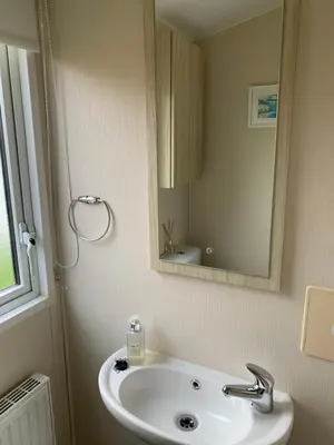 a bathroom with a sink and a mirror at Newquay Bay Resort 63 in Porth