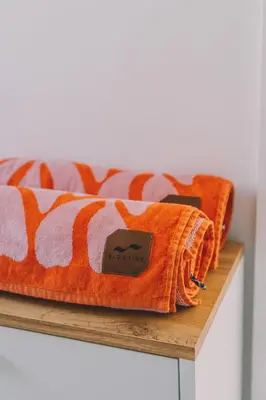 an orange and white blanket on a wooden shelf at Pentire Point - Fully Equipped Eco Escape in Crantock