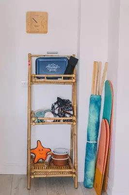 a bamboo shelf with a surfboard and other items at Pentire Point - Fully Equipped Eco Escape in Crantock