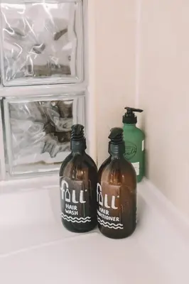 two bottles of liquid sitting on a shelf next to a container at Pentire Point - Fully Equipped Eco Escape in Crantock