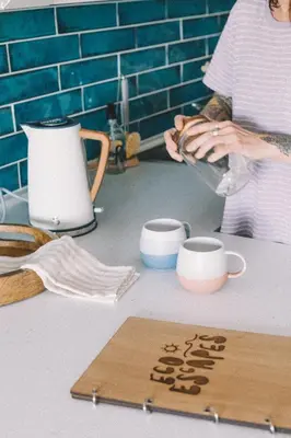 a woman is making a cup on a counter at Pentire Point - Fully Equipped Eco Escape in Crantock